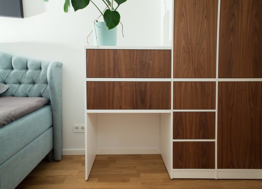 Wooden asymmetrical wardrobe and draws in a bedroom.